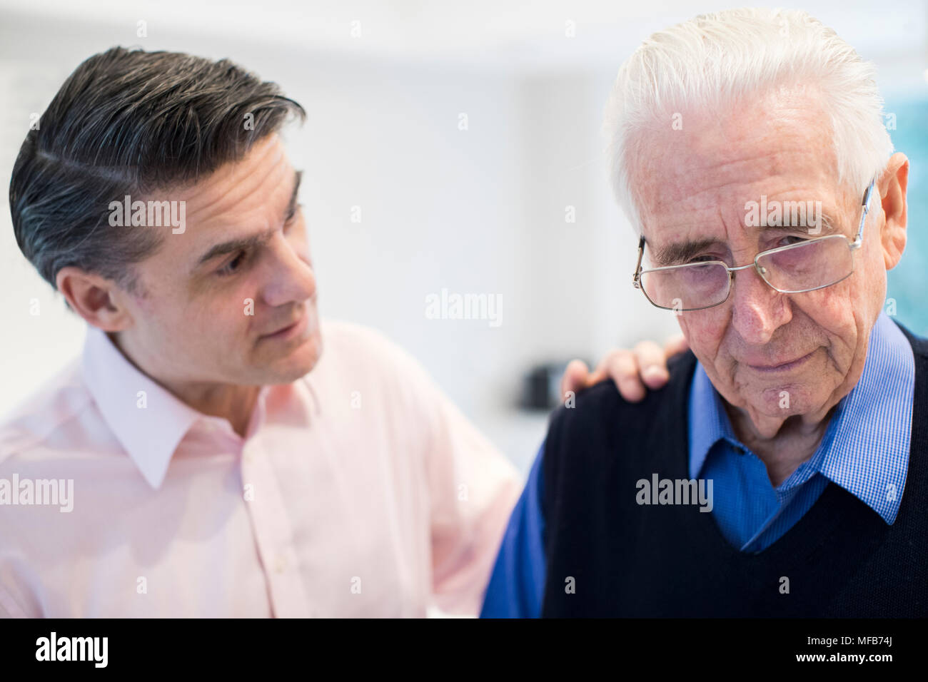 Confused Senior Man With Adult Son At Home Stock Photo