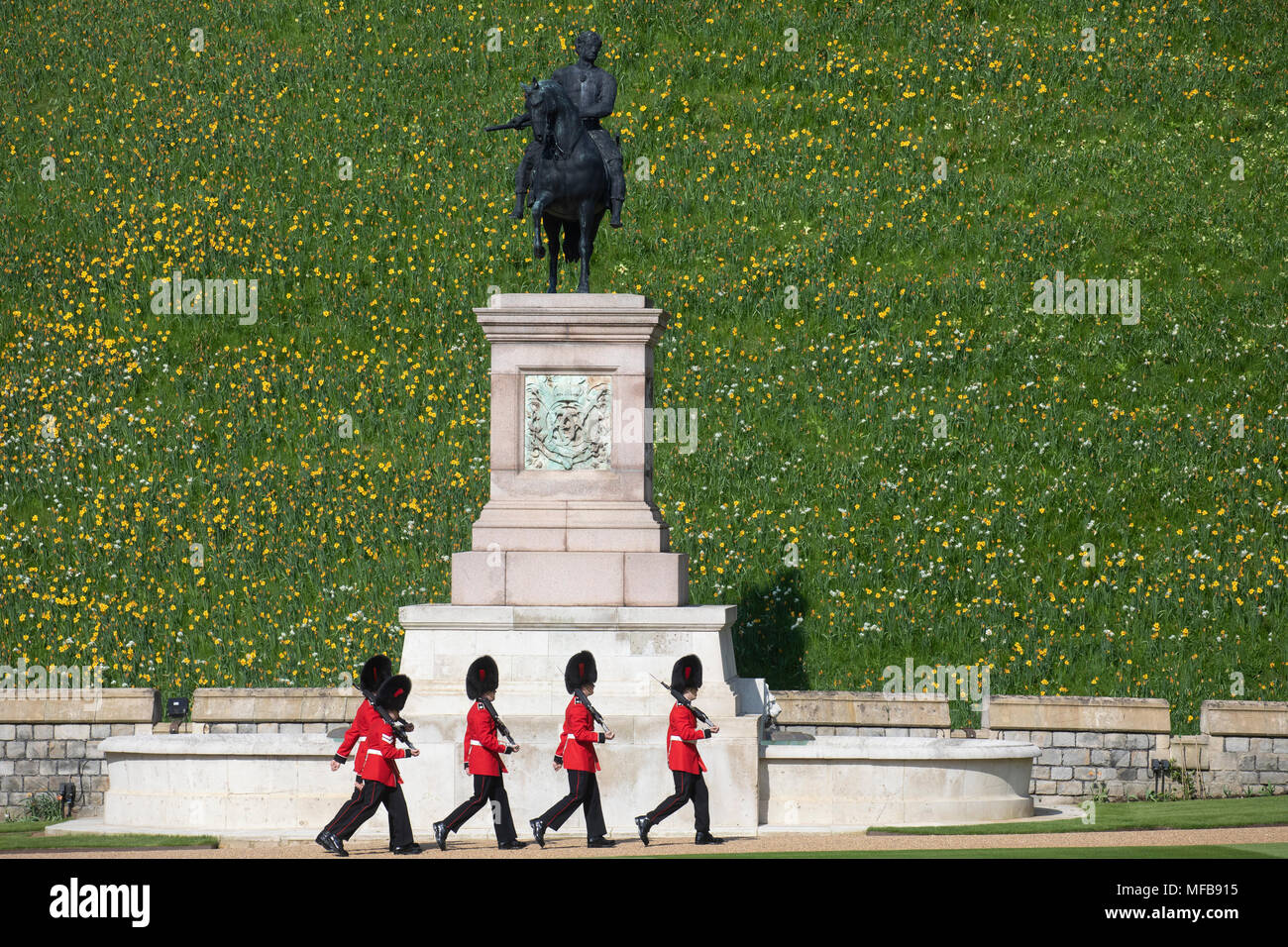 Guardsmen inside Windsor Castle march past the equestrian statue of King Charles II at the foot of the Round Tower's motte. Stock Photo