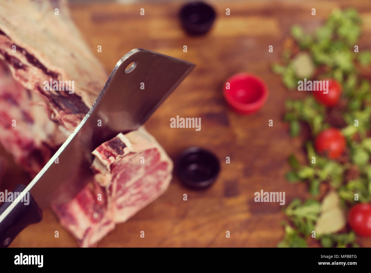 chef using ax while cutting big piece of beef on wooden board in ...