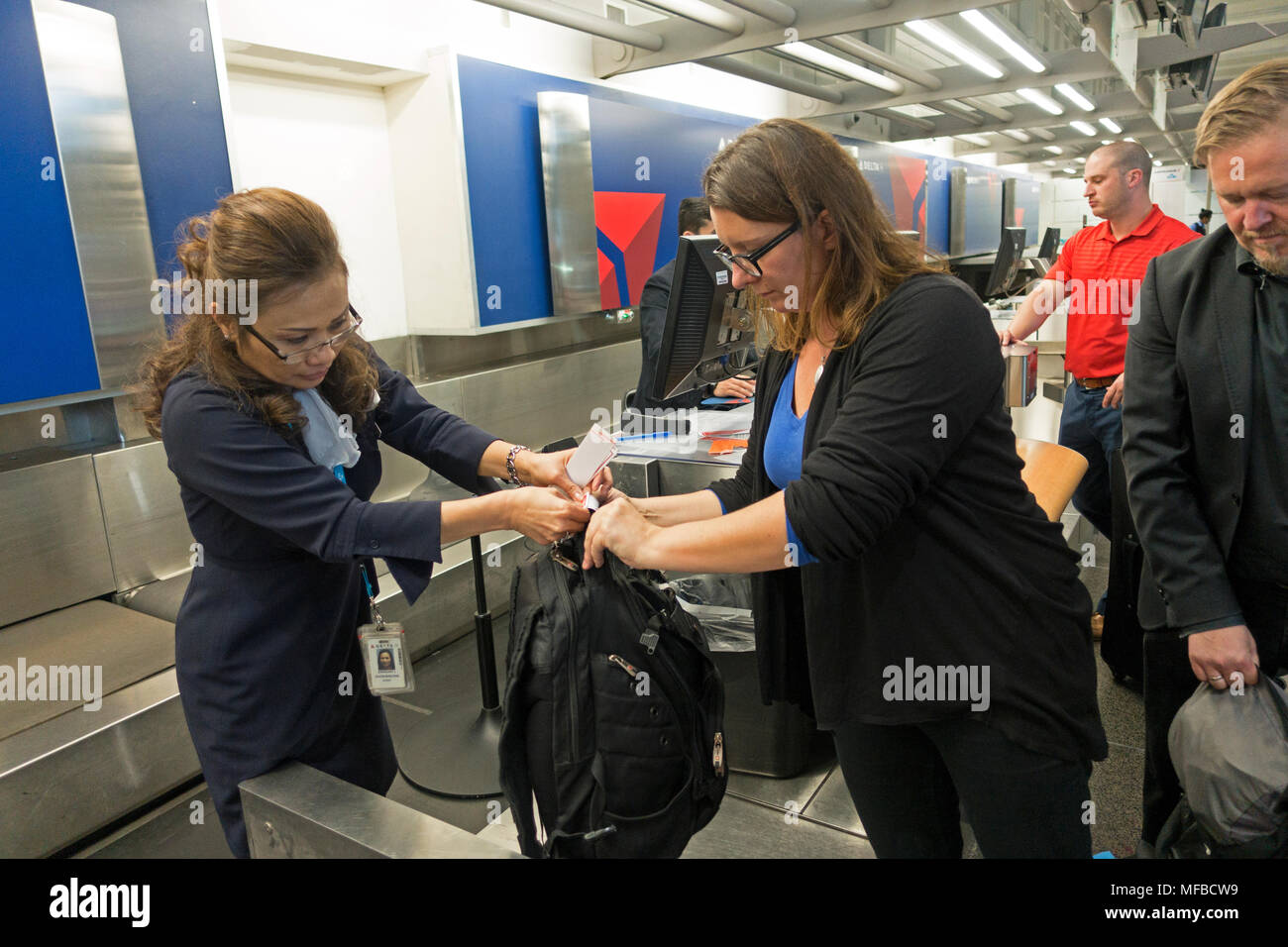 Airline ticket agent puts tag on passengers luggage. Minneapolis St Paul International Airport - Lindbergh Terminal Minneapolis Minnesota MN USA Stock Photo