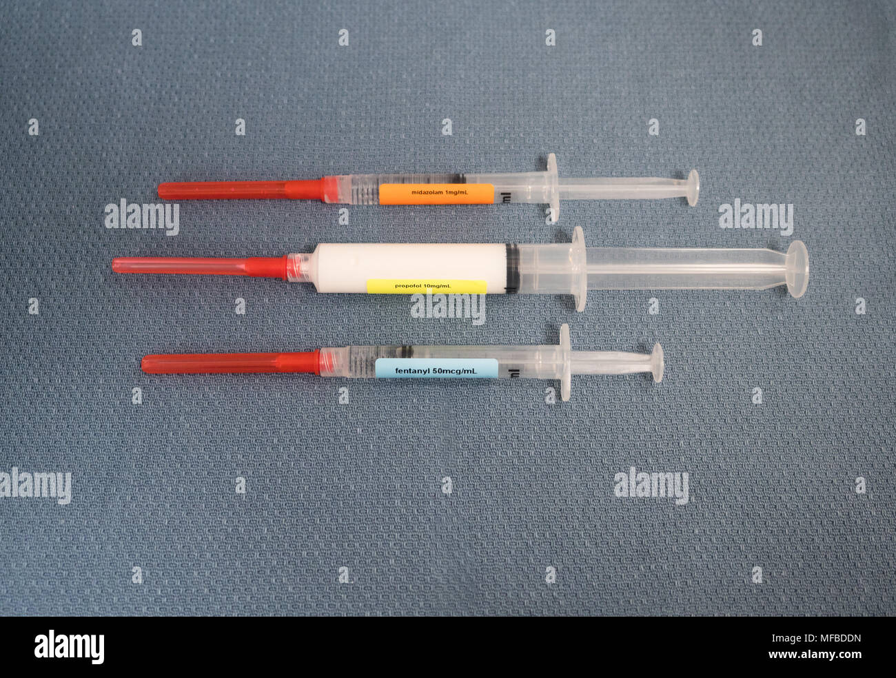 Three labeled syringes with red capped safety needles containing drugs