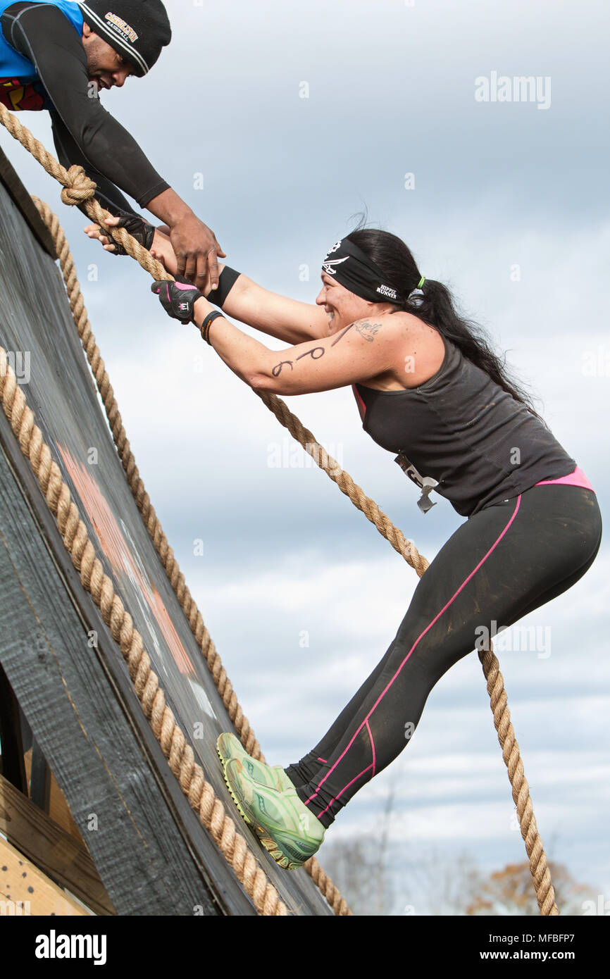 A woman struggles to climb up a wall obstacle using a rope at the Muddy Brute Challenge on November 21, 2015 in Buford, GA. Stock Photo