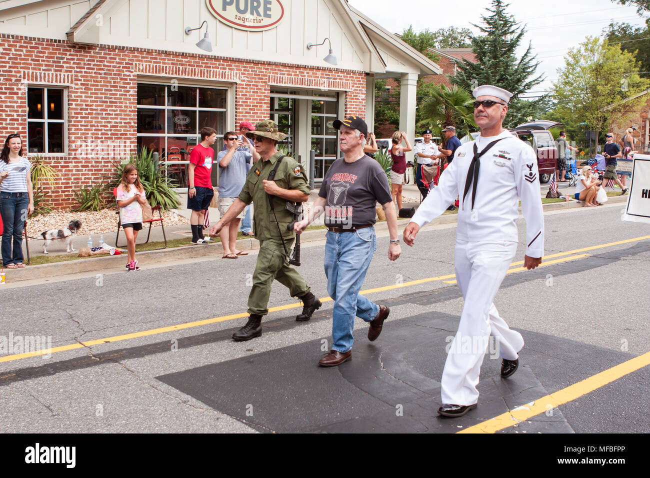 Three combat veterans representing the Army, Navy and Marines walk in the annual Old Soldiers Day Parade on August 1, 2015 in Alpharetta, GA. Stock Photo
