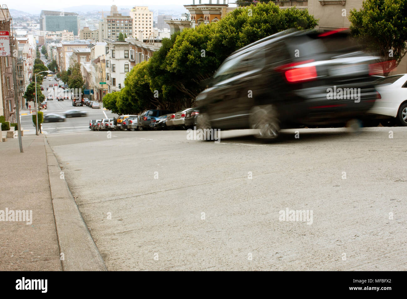 San Francisco, CA, USA - May 18, 2015:  A car motion blurs while braking down a steep hill in the Nob Hill area of San Francisco. Stock Photo