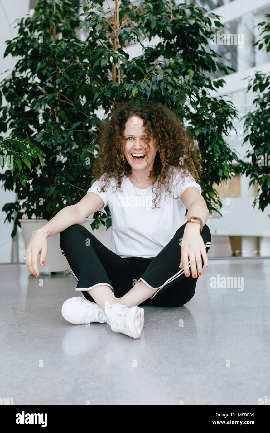 Casual laughing woman sitting on floor Stock Photo