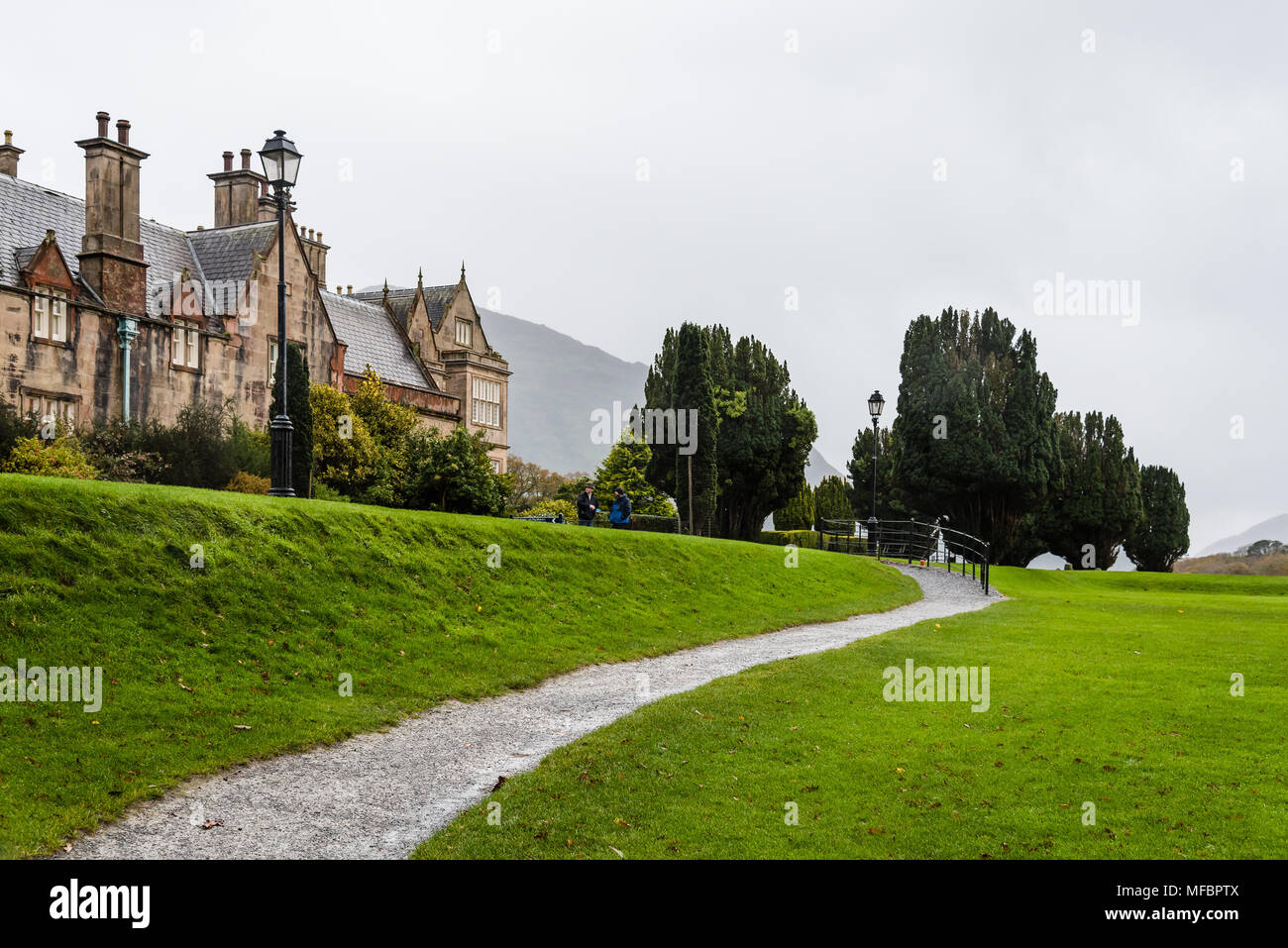 Killarney, Ireland - November 11, 2017: Muckross House and gardens against cloudy sky. It is a mansion designed in Tudor style, located in the The Nat Stock Photo