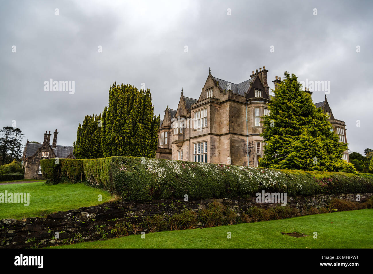 Killarney, Ireland - November 11, 2017: Muckross House and gardens against cloudy sky. It is a mansion designed in Tudor style, located in the The Nat Stock Photo