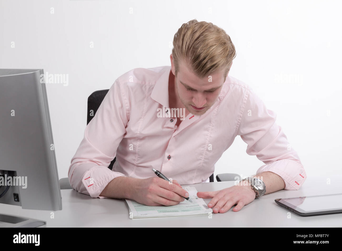 Young man working at desk on paper work Stock Photo