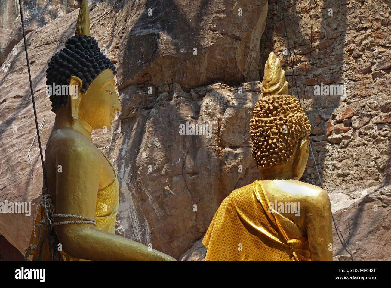 Two Buddha statues in front of sandstone rock face at Wat Tham Kong Phen temple, near Phu Pan Mountain, Nong Bua, Udon Thani, Thailand Stock Photo