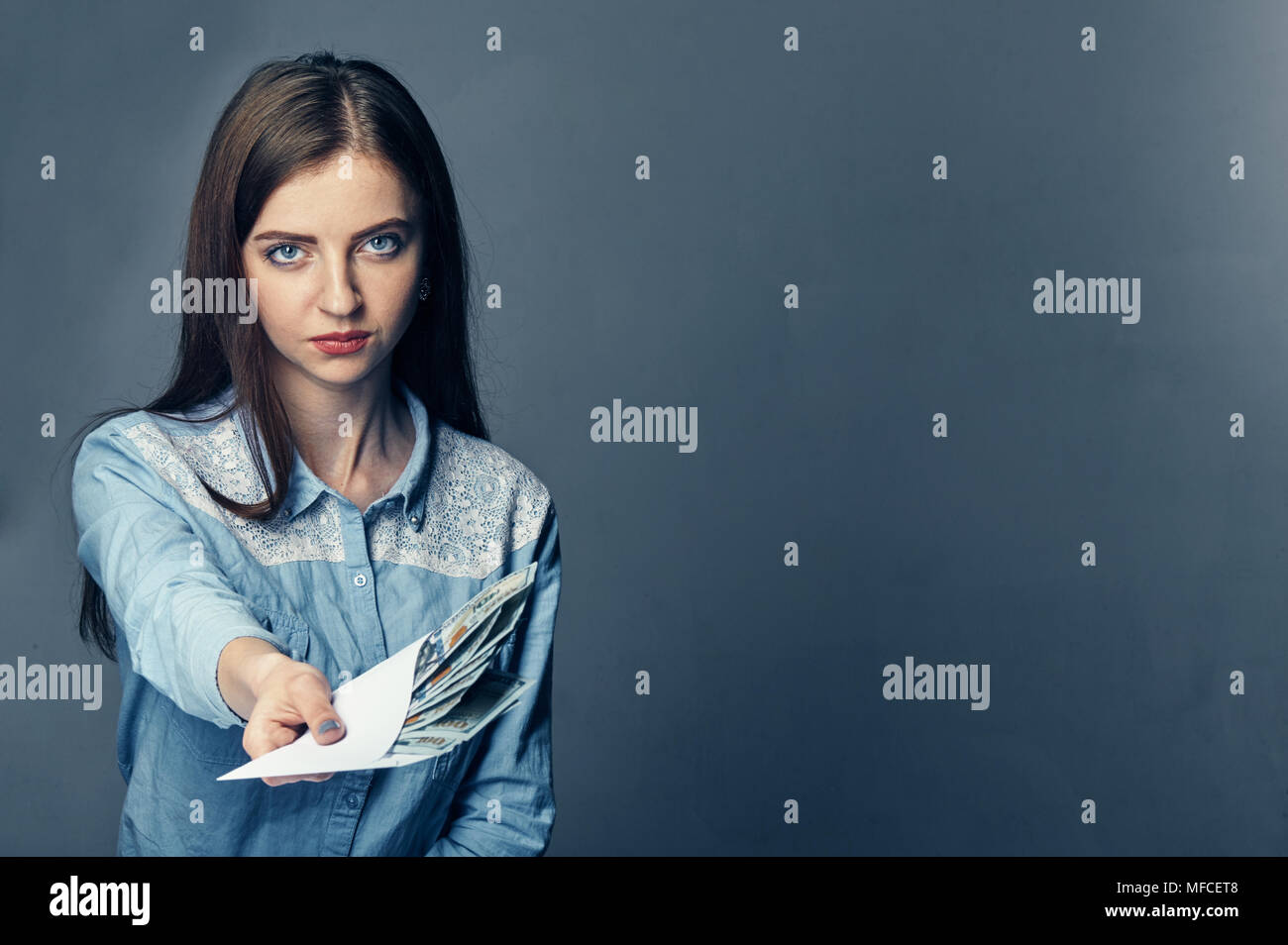 The person's hand gives a bribe in dollars. American dollars in hand. Woman offers money on a dark background. A pile of American money in hand on a dark background. Stock Photo