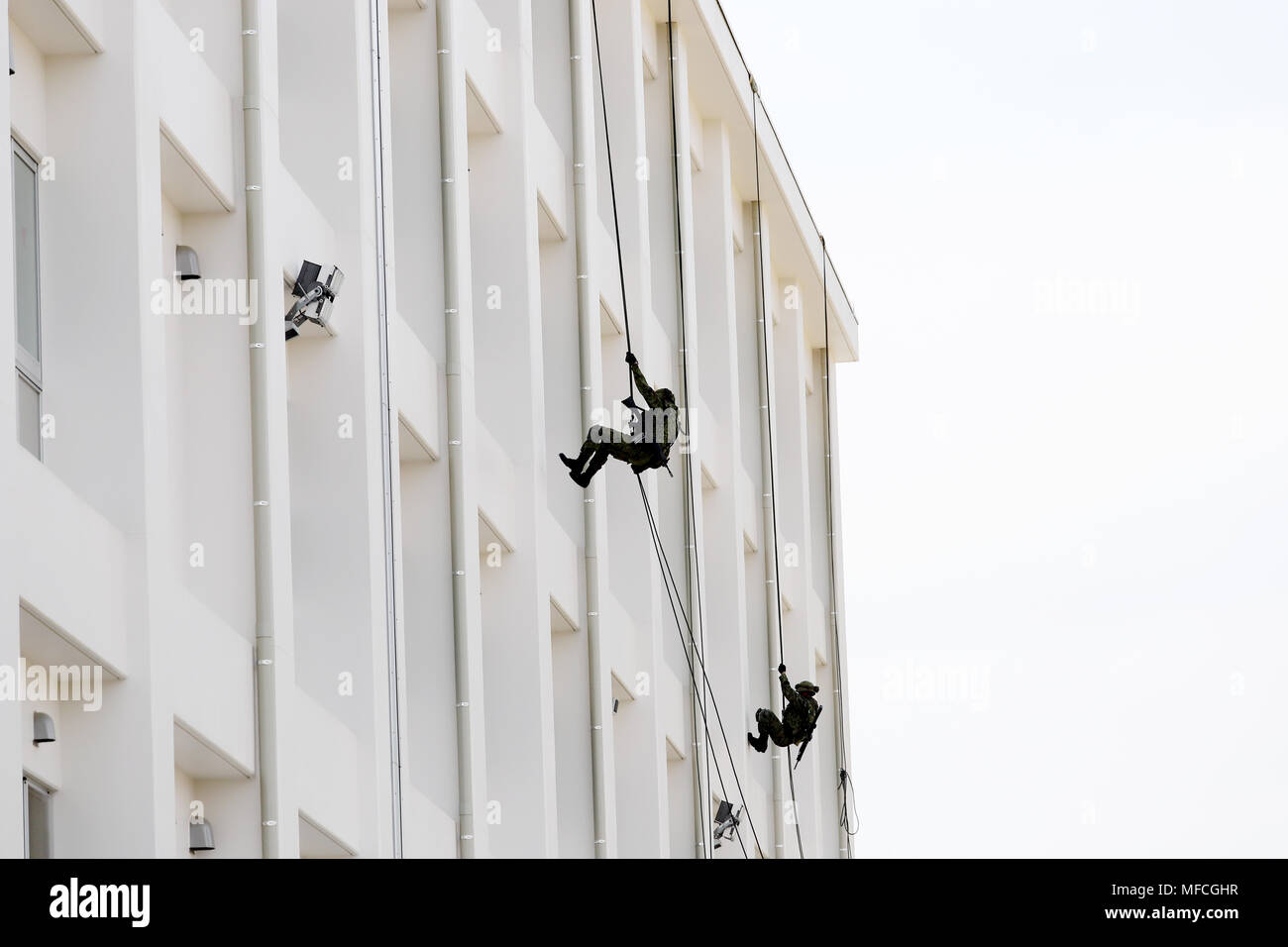 Japanese military men rappelling down the rope from building Stock Photo