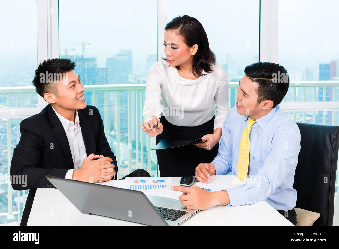 Asian banker counseling man in office Stock Photo