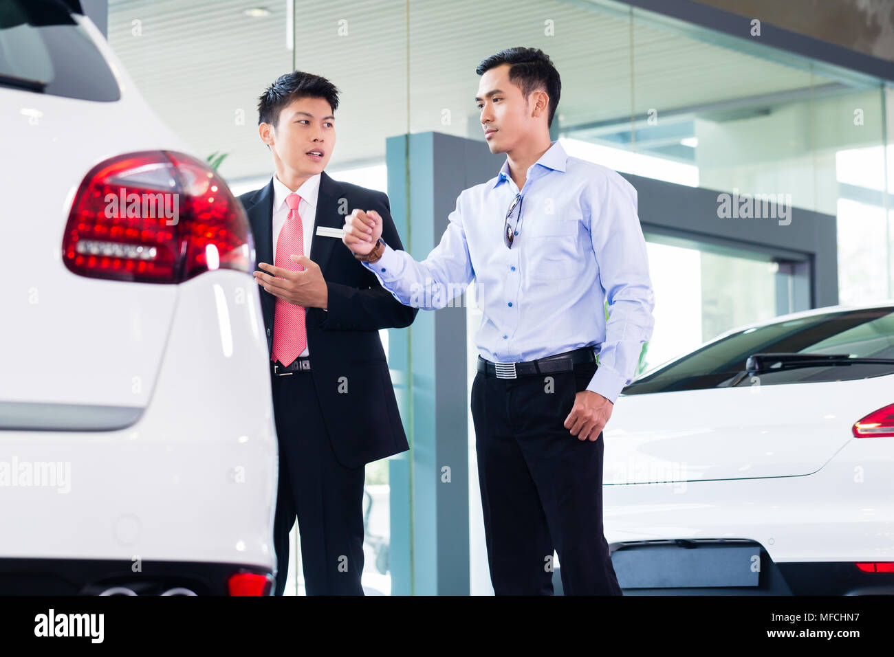 Asian Car Salesman selling auto to customer Stock Photo