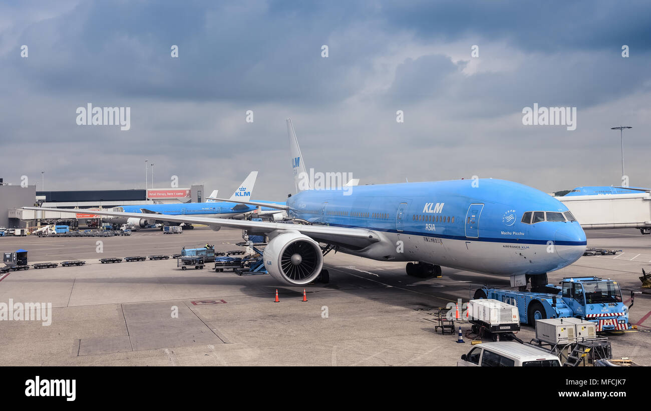 Amsterdam / Netherlands - 07.09.2017: KLM airplane Boeing 777 at the Schiphol Airport standing by the terminal withe the dark blue clouds in the backg Stock Photo
