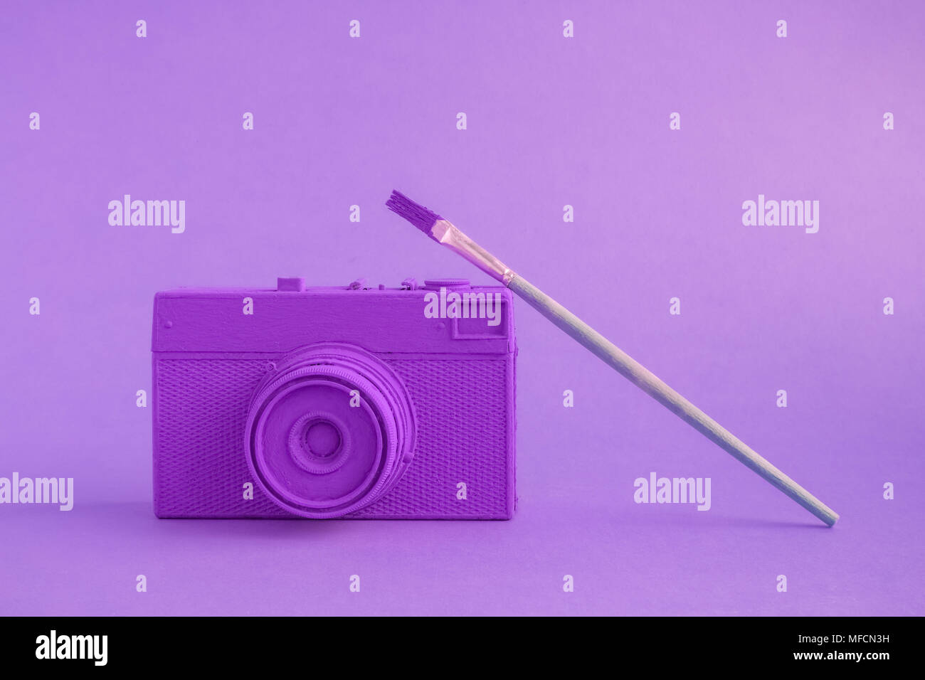 Purple retro film photo camera with paintbrush minimal art creative concept. Stock Photo