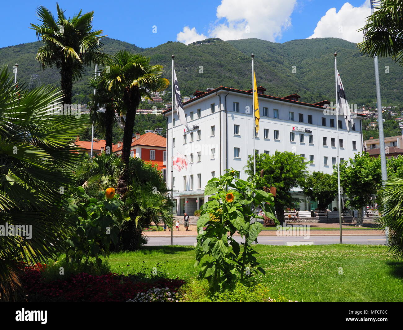 LOCARNO, SWITZERLAND on JULY 2017: Tropical palms in park with flags on  mast at square and colorful buildings in european city center at canton of  Tic Stock Photo - Alamy