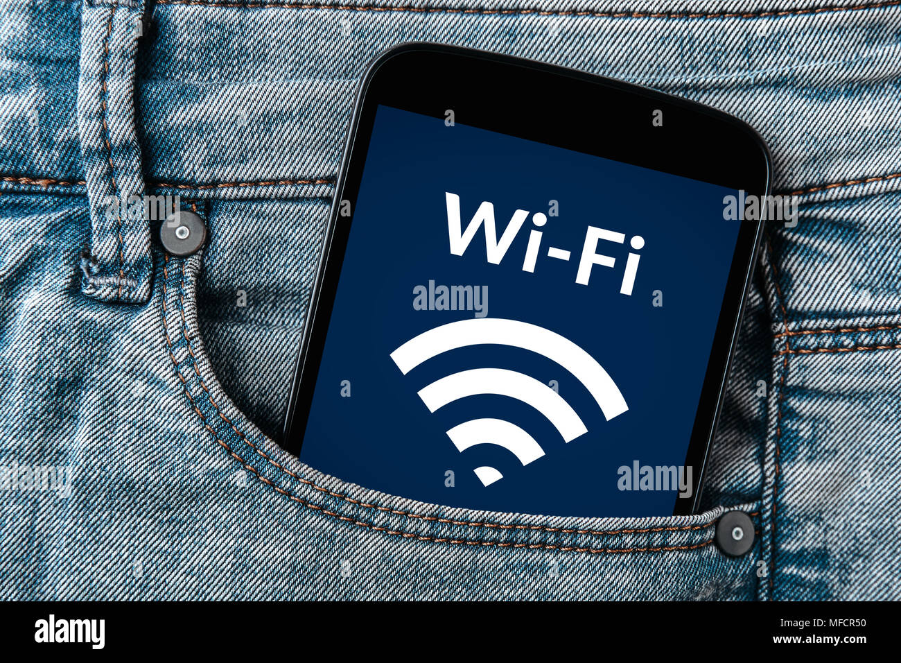 Free wifi concept on smartphone screen in jeans pocket. All screen content is designed by me. Flat lay Stock Photo