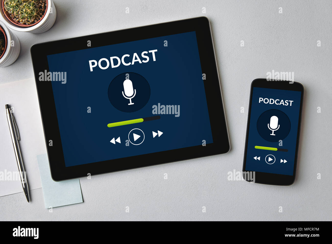 Podcast concept on tablet and smartphone screen over gray table. All screen content is designed by me. Flat lay Stock Photo
