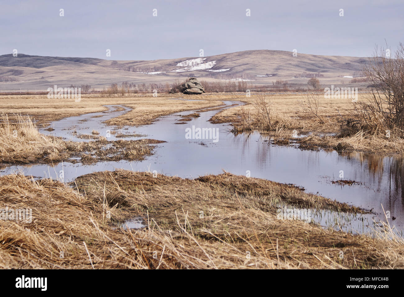 Dry grass. Grey sky. Water. Mountain landscape. Stock Photo