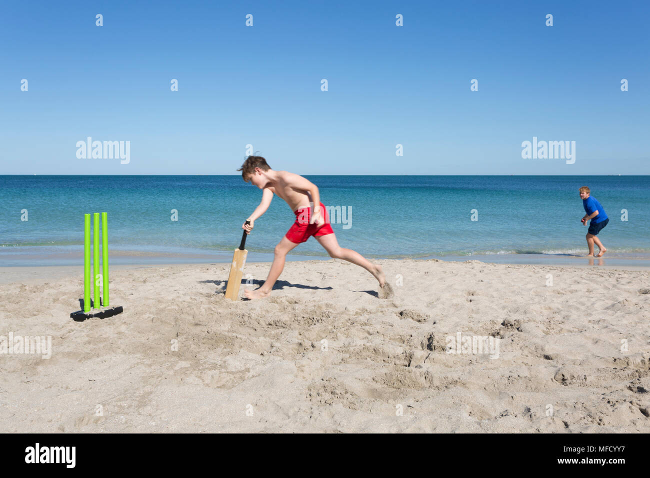 Two siblings or friends playing Beach Cricket. Stock Photo