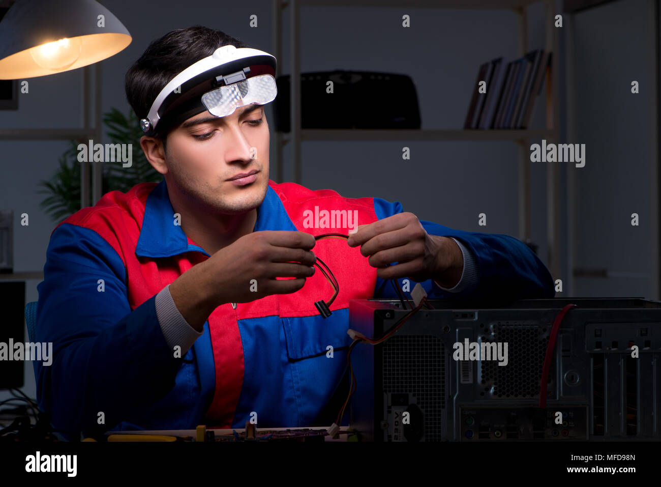 Computer specialist repairing PC late at night Stock Photo - Alamy