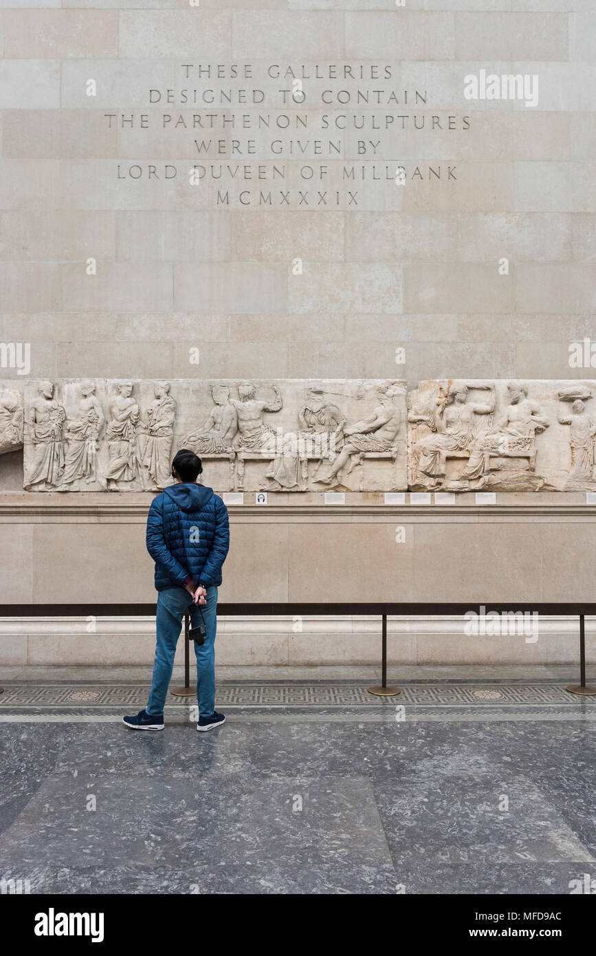 London. England. British Museum, person looking at the Parthenon Frieze (Elgin Marbles), Four Olympian gods seated on stools (central panel), from the Stock Photo