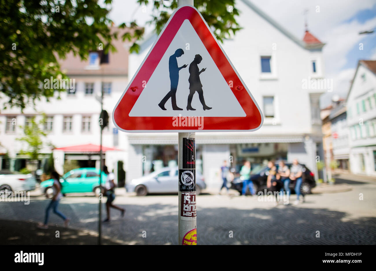 25 April 2018, Germany, Reutlingen: A sign warning against 'Smombies' beside a school. The made-up word is a mixture of 'Smartphone' and 'Zombie' and stands for people who walk across streets with their eyes glued to their phones. Photo: Christoph Schmidt/dpa Stock Photo