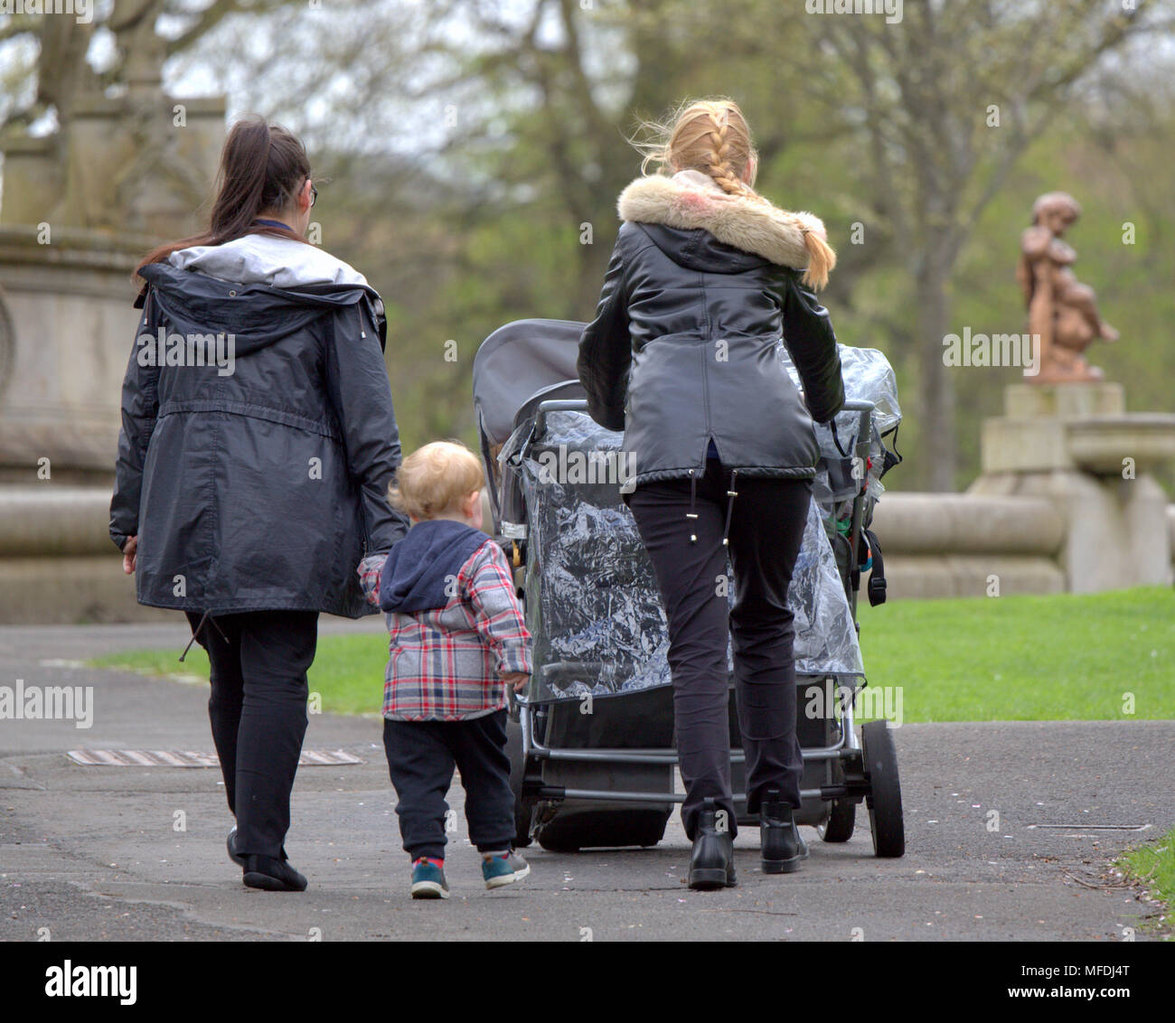 Glasgow, Scotland, UK 25th April. UK Weather: women girls with pram and child pushing buggy mirrored by cherub kelvingrove park fountain  Sunshine and showers as the locals and tourists enjoy the beginning of summer. Gerard Ferry/Alamy news Stock Photo