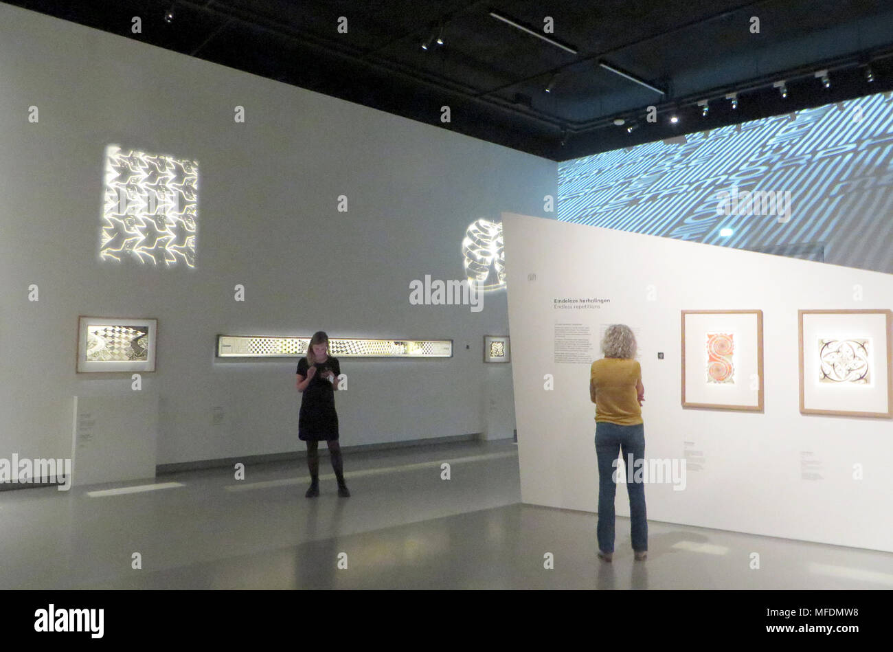 24 April 2018, Netherlands, Leeuwarden: Visitors at the exhibition 'Escher on the road' in the Frisian museum. The cryptic, mostly black and white works from M.C. Escher are popular motives for t-shirts and maths books. The exhibition is running from the 28 April to the 28 October 2018. Photo: Annette Birschel/dpa Stock Photo