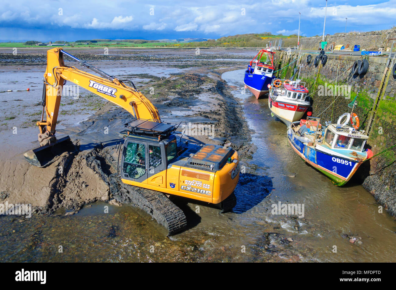 Garlieston, Dumfries & Galloway, Scotland, UK. 25th April, 2018. UK Weather. Mechanical plant on the beach at low tide to clear rocks, boulders and the build up of silt to help clear the water way around the harbour on a sunny afternoon. Credit: Skully/Alamy Live News Stock Photo