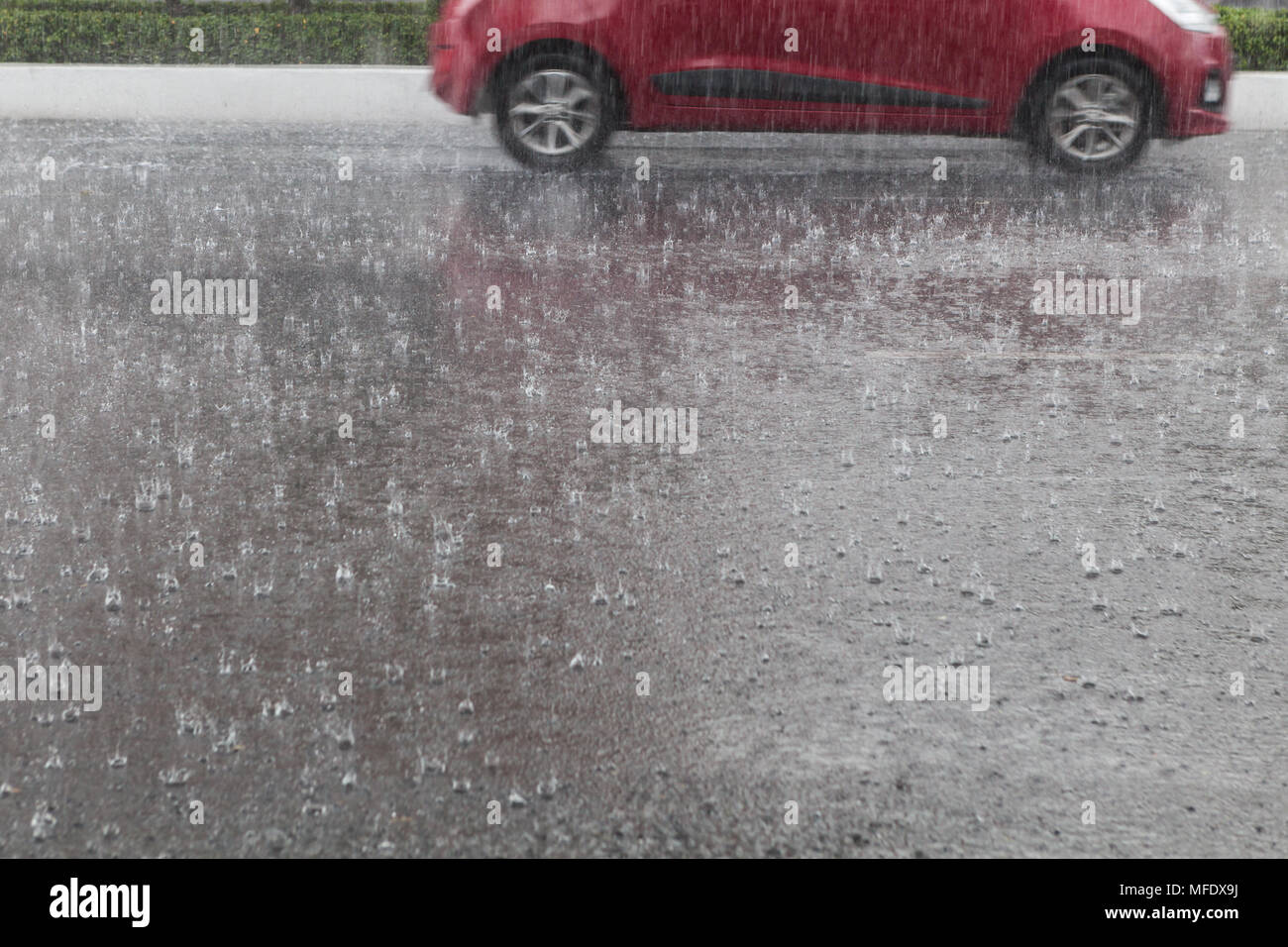 Heavy rain on the street, car driving in the background Stock Photo