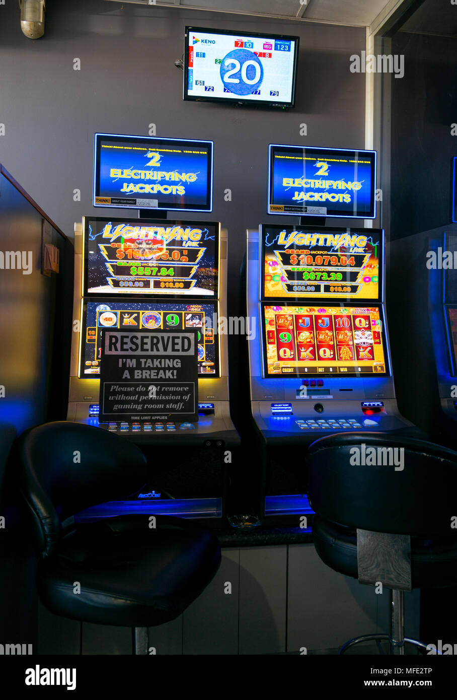 two poker slot machines at glen innes rsl club, one with reserve sign and Kino display on wall above Stock Photo