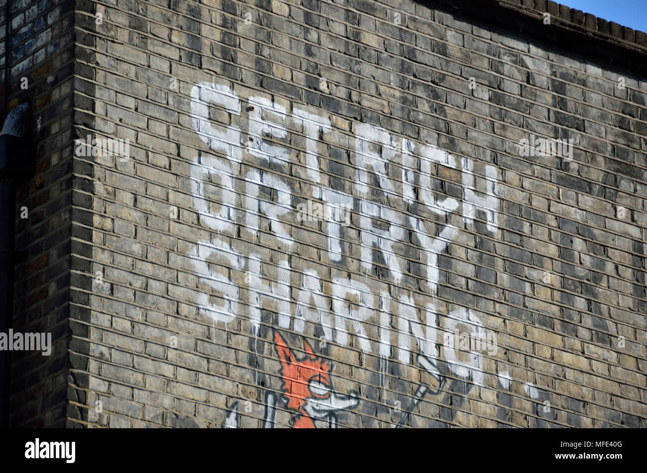 ’Get rich or try sharing’ slogan painted on a wall Stock Photo