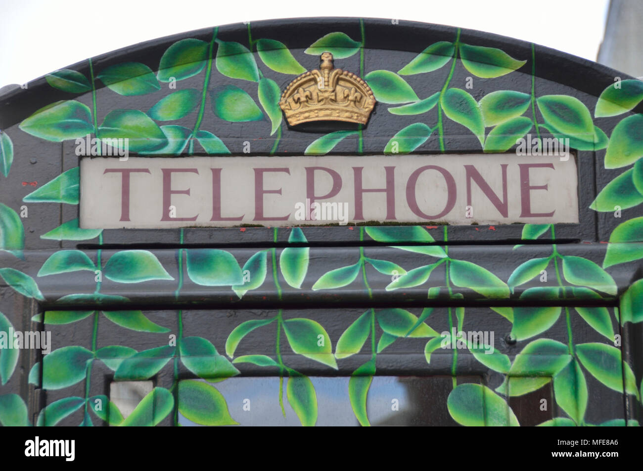 Traditional UK telephone box painted with a leaf design. Stock Photo