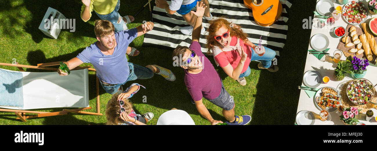 Young people dancing, drinking and eating at a party outdoors Stock
