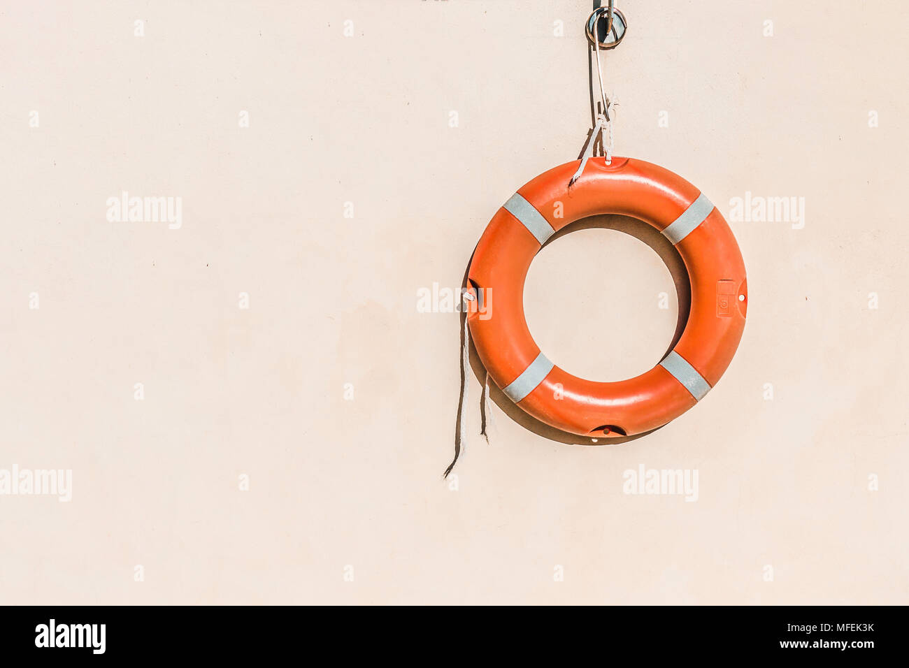 Lifeguard equipment, orange lifebelt with rope hang on the wall near