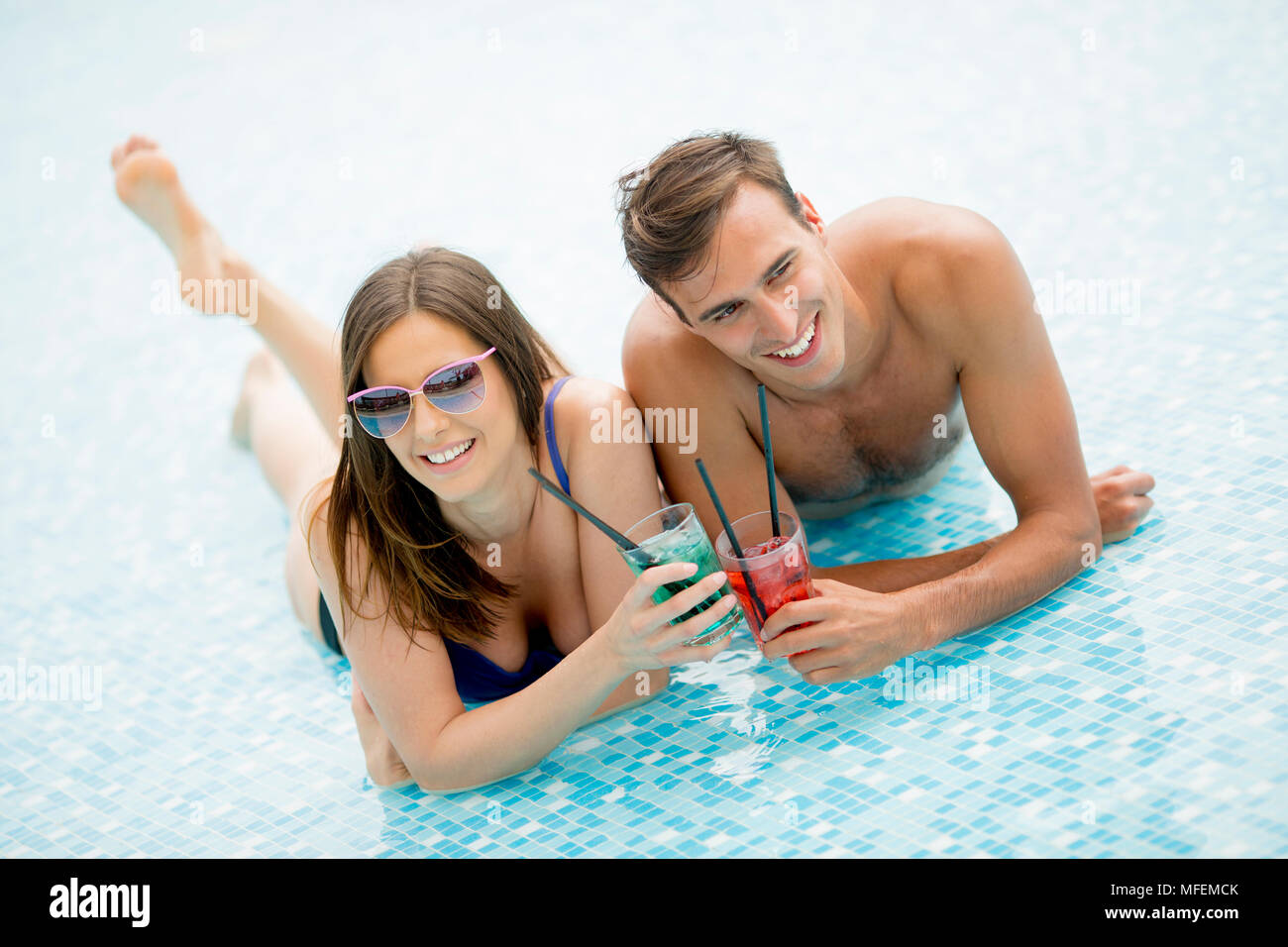Young couple drinking cocktails in the swimming pool at summertime Stock Photo