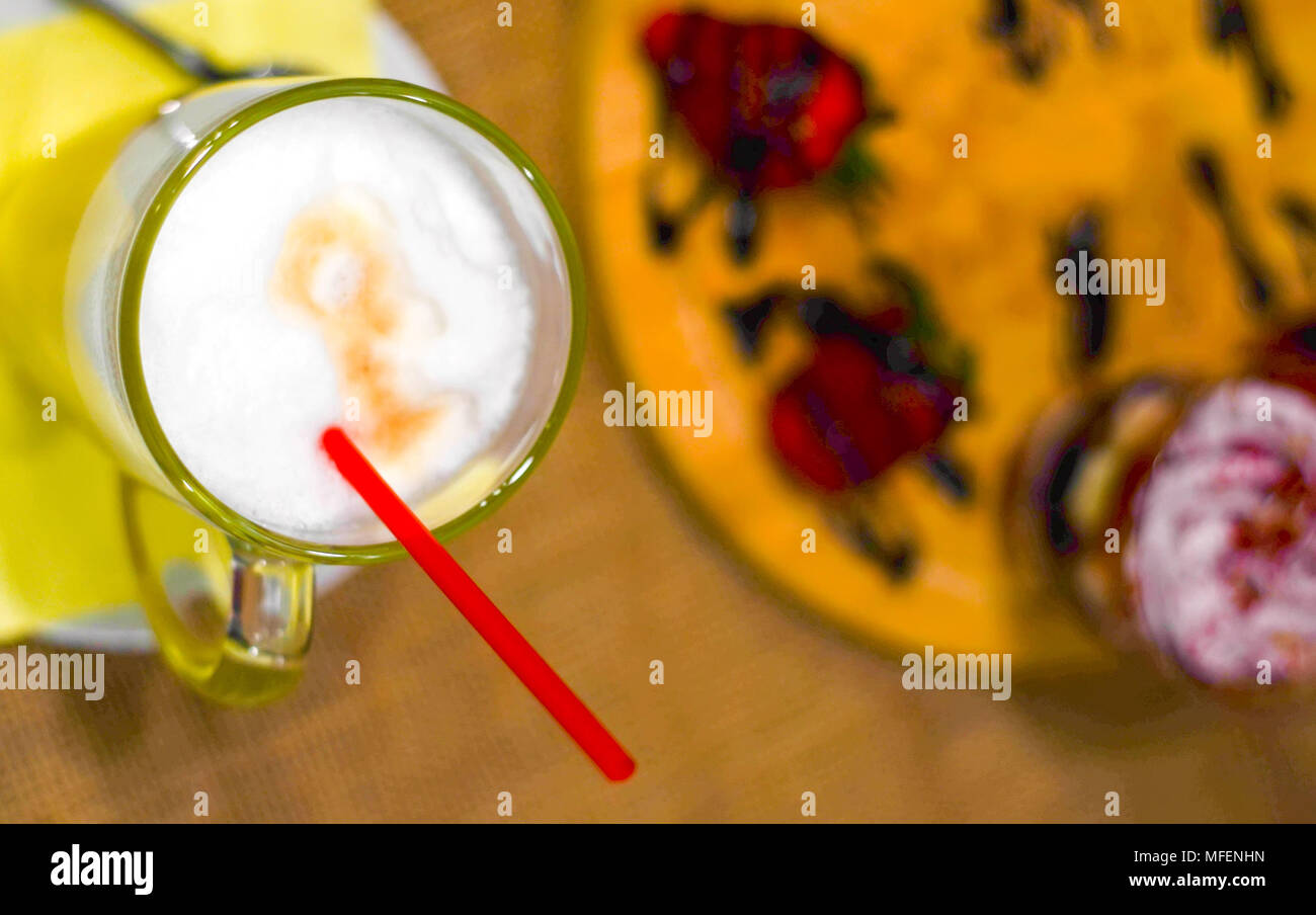 The glass of coffee latte with red straw on dessert strawberry trifle background.Top view.Flat lay.Copy space. Stock Photo