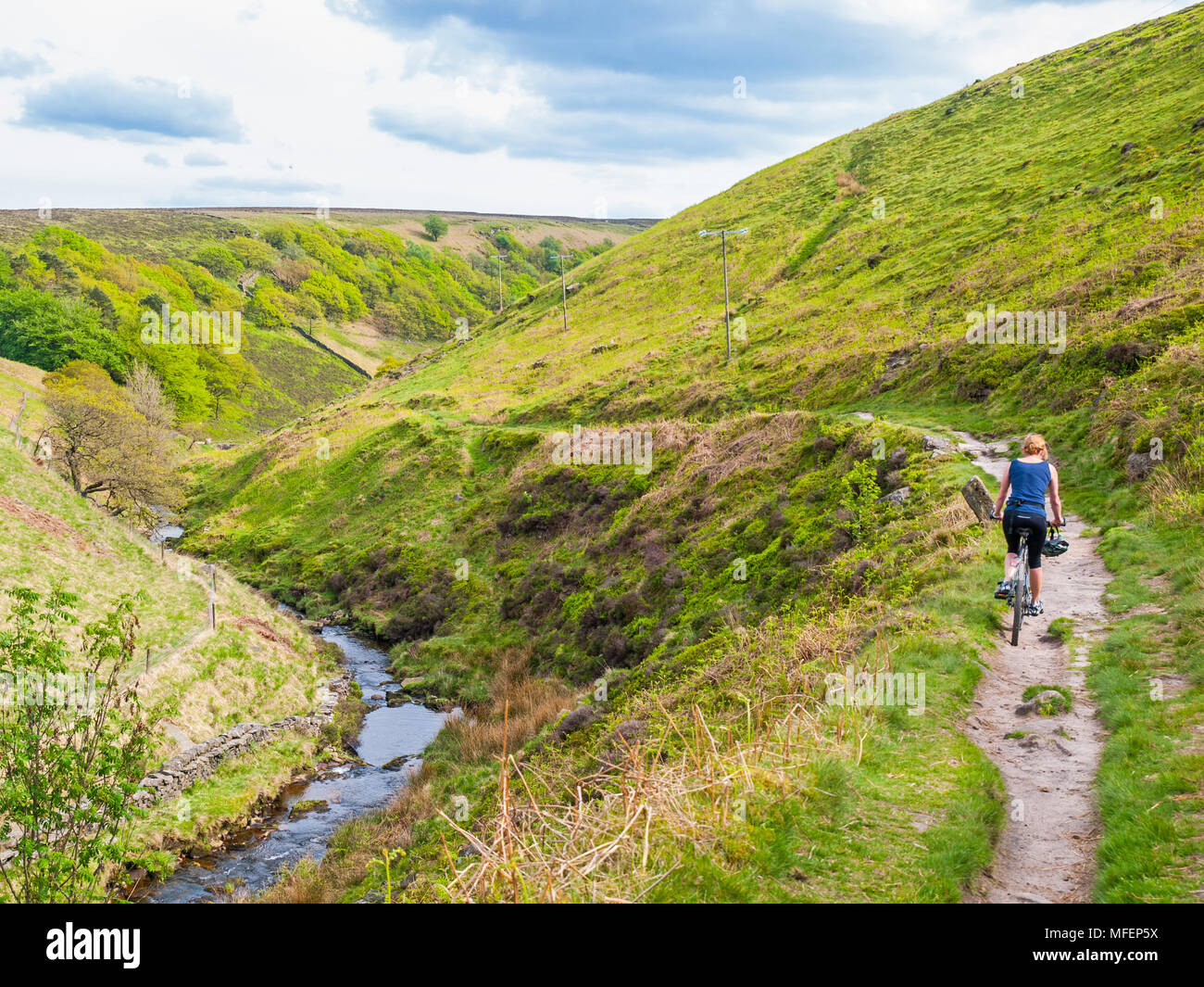 Female cyclist on a bridleway near Three Shire Heads, Peak District National Park Stock Photo