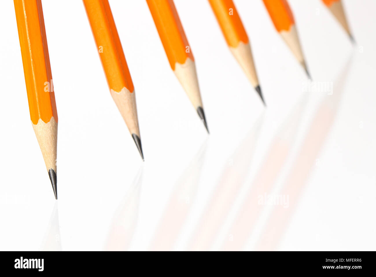 Few wooden yellow pencils standing in a row on white background Stock Photo