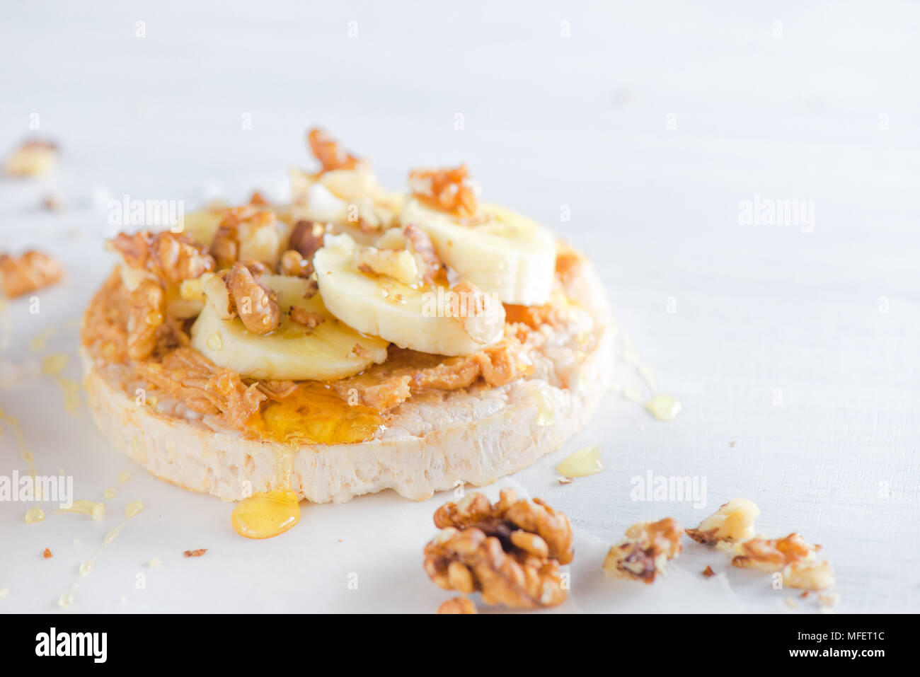 Crisp bread with caramelized banana, walnuts and peanut butter. Healthy breakfast concept in a high key. Stock Photo