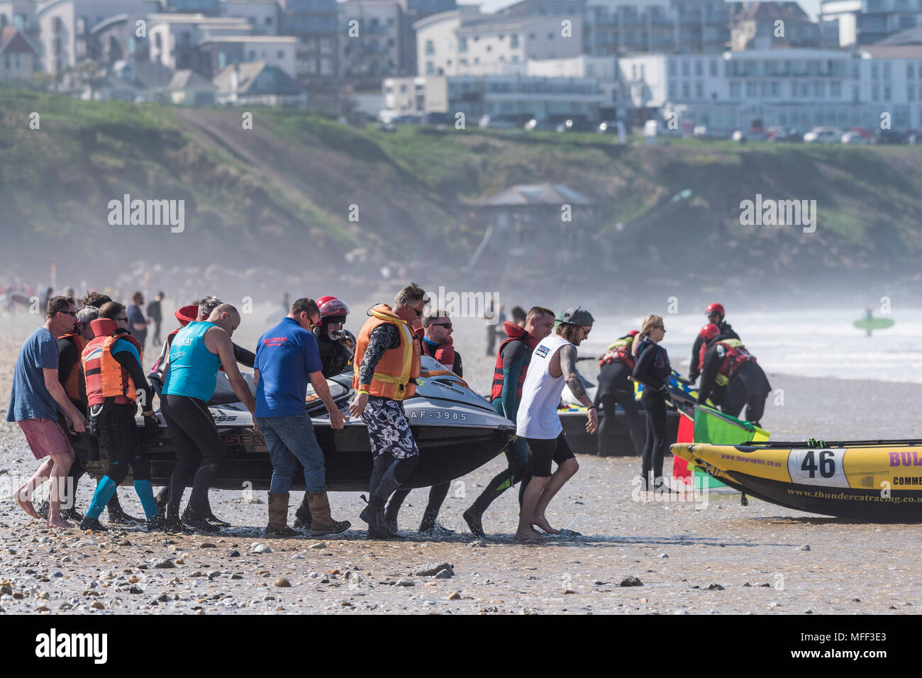 People helping to carry a jetski across the beach at Fistral in Newquay in Cornwall. Stock Photo
