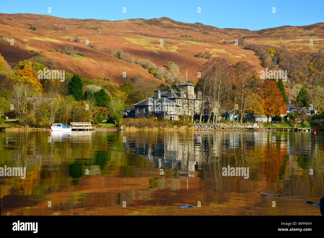 Looking across Loch Earn to St Fillans village, Scotland UK  Autumn colours and reflections clear blue sky sunny day October 2017 Stock Photo