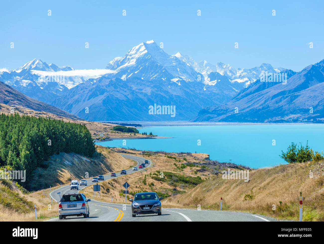 new zealand south island new zealand  cars travelling on a winding road to mount cook national park by the side of lake pukaki new zealand Stock Photo