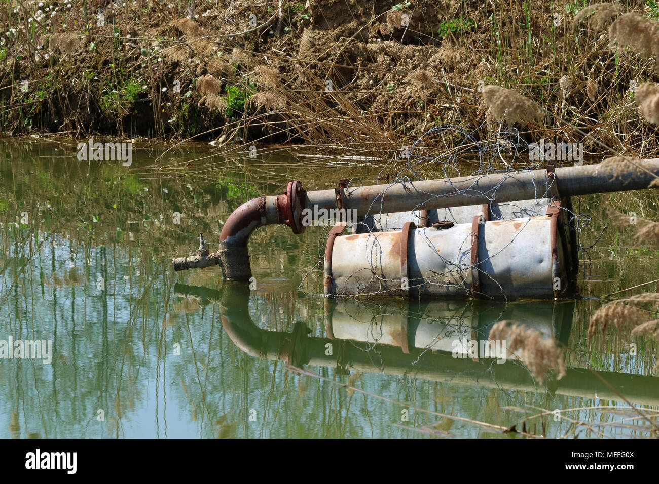 sewage pipe in the lake on floating barrels Stock Photo