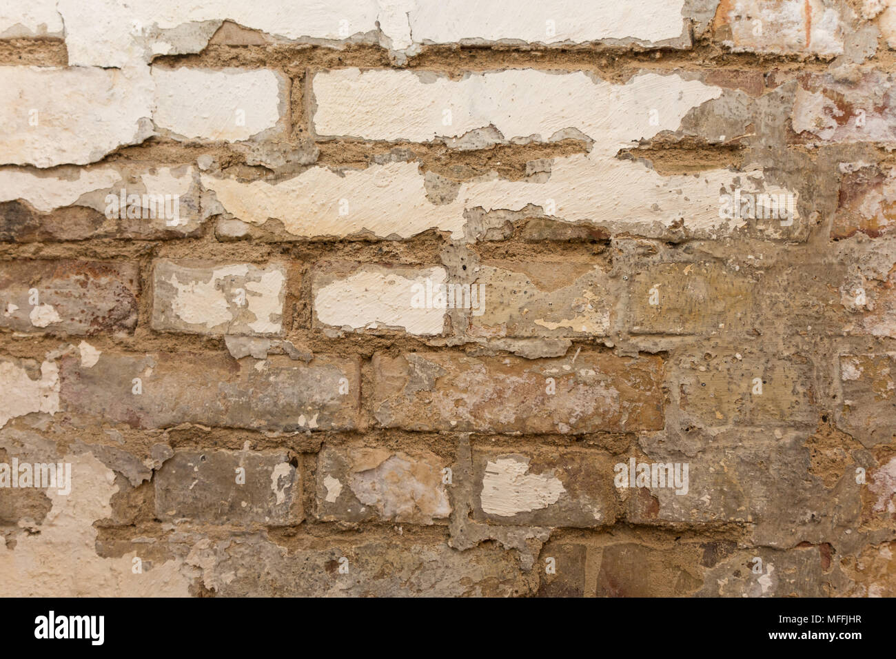 Rough brick wall with white paint coming loose Stock Photo