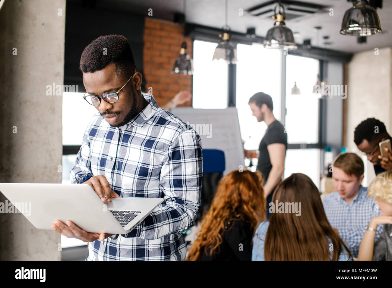 Afro programmer in casual outfit is fixing broken laptop at workplace Stock Photo