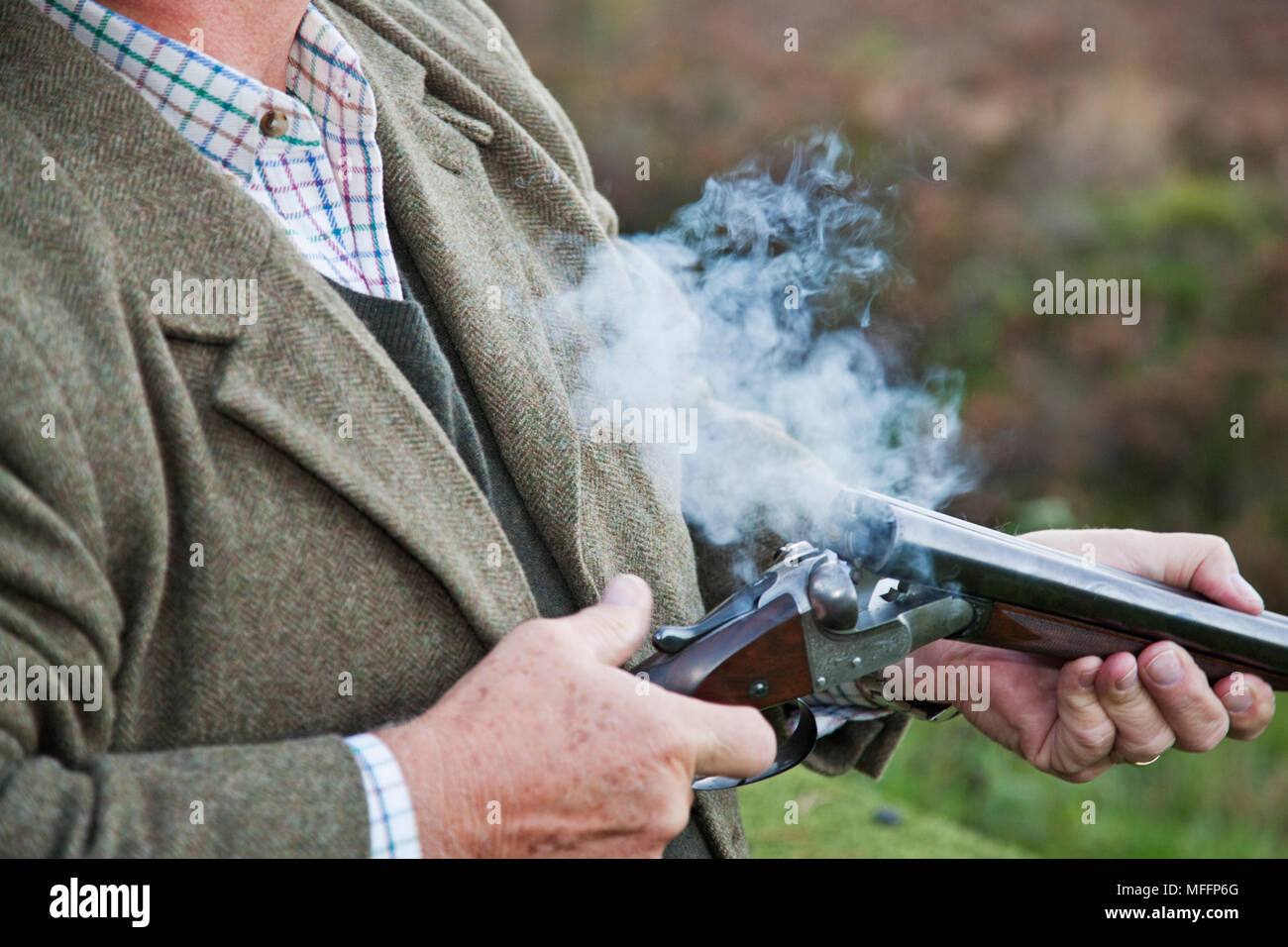 Detail photograph of well dressed man holding a shotgun during a pheasant shoot. Stock Photo