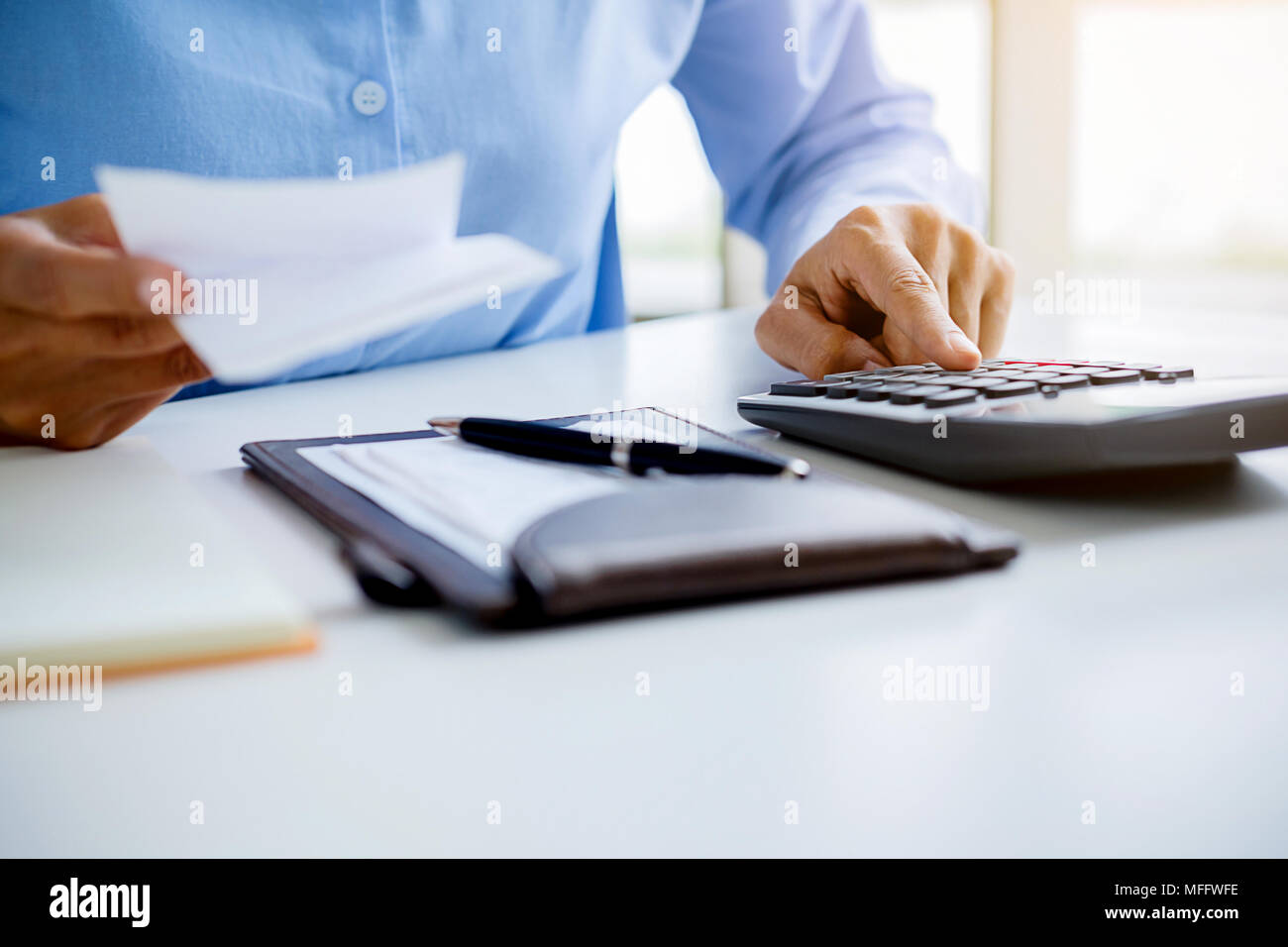 Woman with bills and calculator. Woman using calculator to calculate bills at the table in office. Calculation of costs. Stock Photo