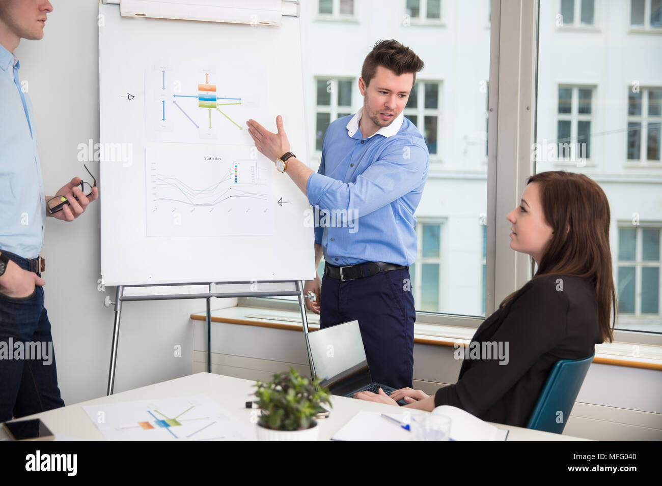 Businessman In Formals Giving Presentation To Colleagues Stock Photo